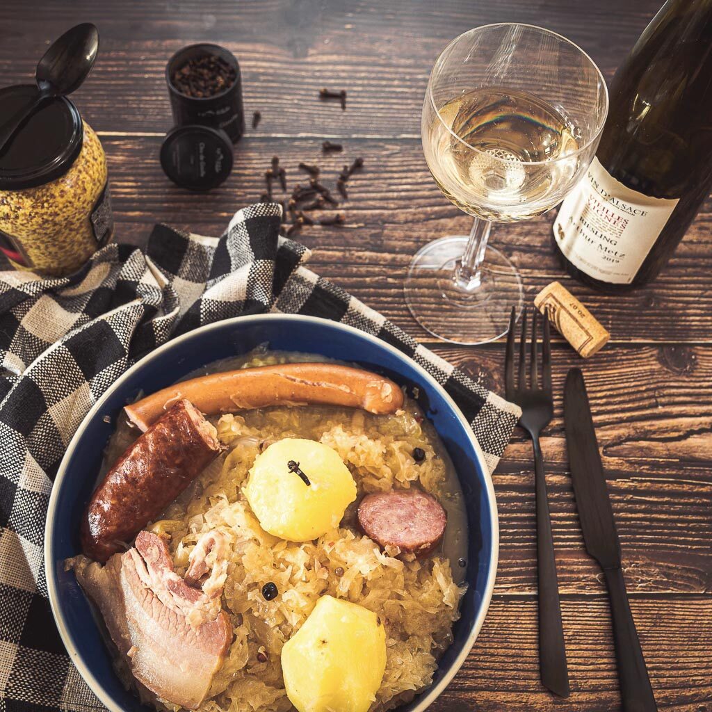 assiette de choucroute maison avec diverses charcuteries, une bouteille de vin et un verre, ainsi qu'une boîte de clou de girofle de Spyceez
