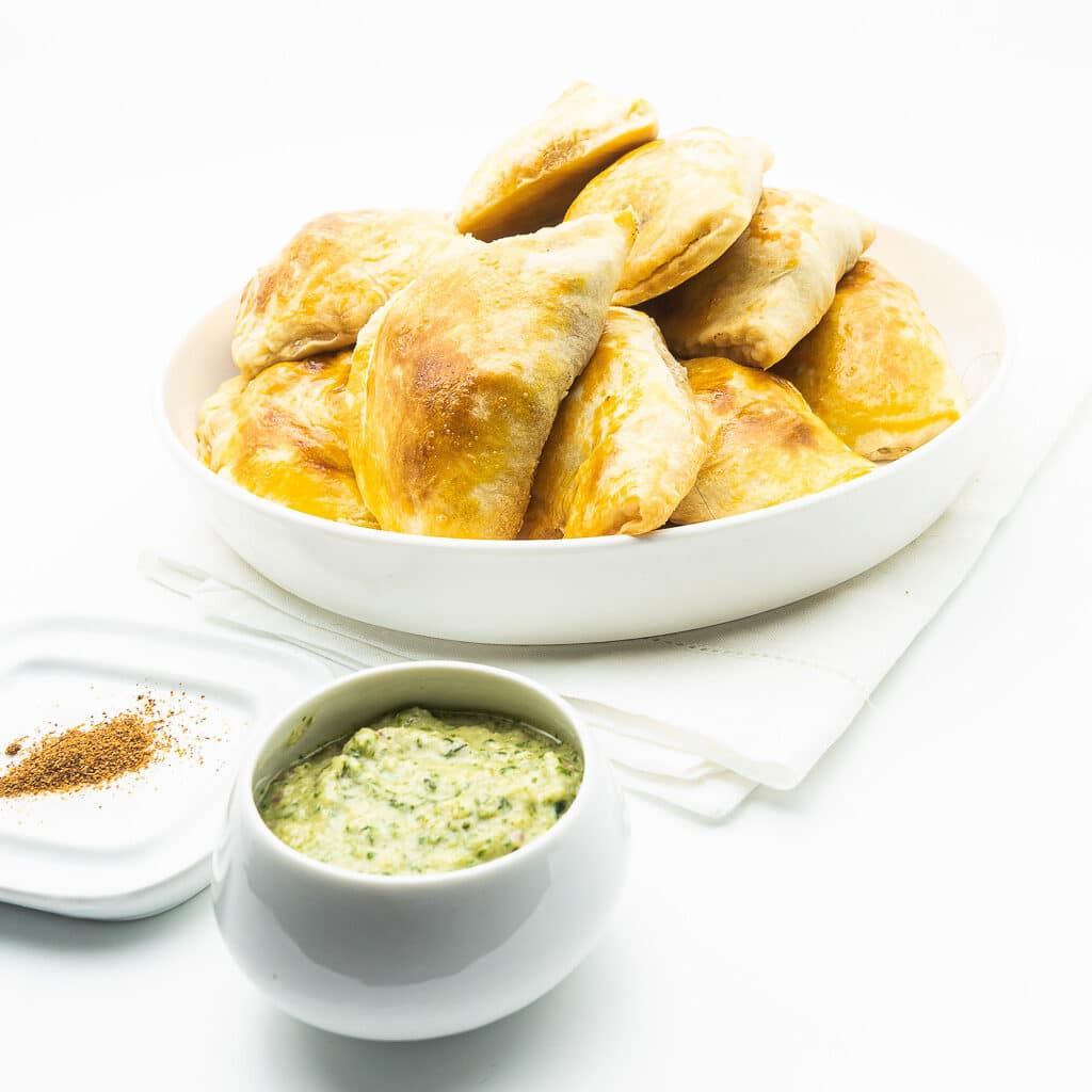 Sur un fond très blanc, une assiette d'empanadas maison à la viande pimentés au pili-pili