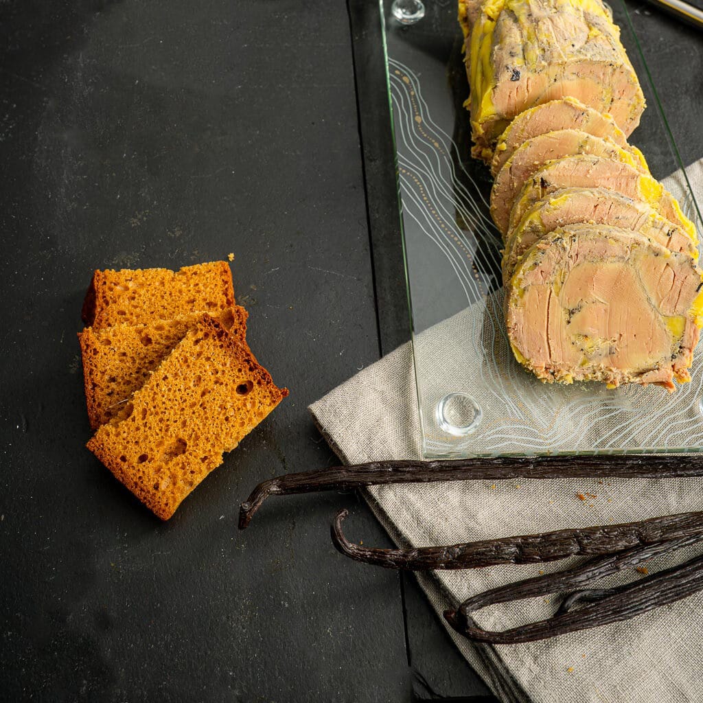 foie gras maison à la vanille présenté en tranches accompagné de pains d'épices et de gousses de vanille