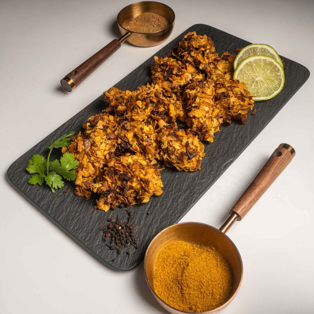 une présentation de nuggets de poulets panés aux corn-flakes et oignons frits et de ses épices