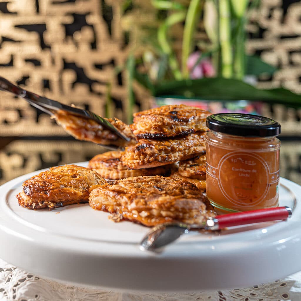 plateau de chaussons aux pommes et à la confiture de litchi présentés avec un pot de cette confiture