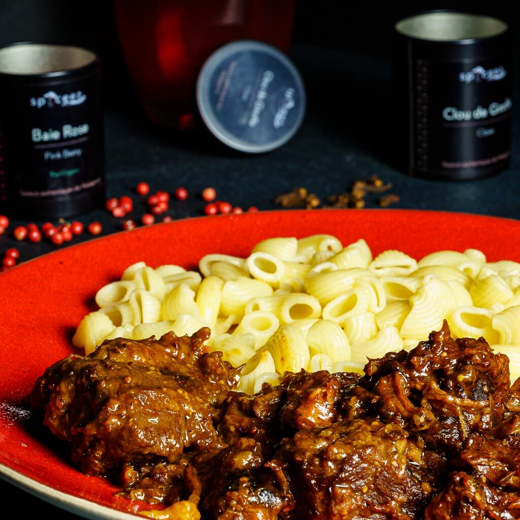 Une onctueuse carbonnade flamande sur assiette rouge servie avec des pâtes au beurre